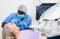 Dentist is treating female patient which is sitting in dental chair in clinic Royalty Free Stock Photo