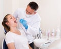 Dentist is treating female patient which is sitting in dental chair Royalty Free Stock Photo