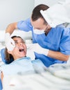 Dentist is treating female patient which is sitting in dental chair Royalty Free Stock Photo