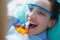 Dentist treating teeth to woman patient using curing light and dental instruments Royalty Free Stock Photo