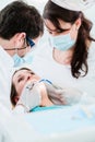 Dentist treating woman patient with drill