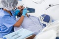 Dentist in uniform is examinating man on chair