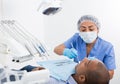 Dentist in uniform is examinating man on chair