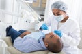 Dentist in uniform is examinating man on chair