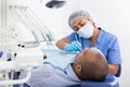 Dentist in uniform is examinating man on chair