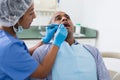 Dentist in uniform is examinating man on chair