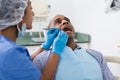 Dentist in uniform is examinating man on chair