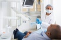 Dentist in uniform is examinating man on chair