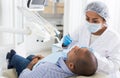 Dentist in uniform is examinating man on chair