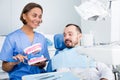 Dentist in uniform with maket of jaw is telling about healthcare