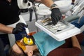 Dentist uses dental curing light for fixing patient`s teeth and takes another dental instrument from a tray