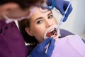 Dentist uses dental tools and mirror to check the teeth of woman patient