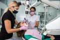 Dentist uses professional equipment to whiten the patient`s teeth in the clinic