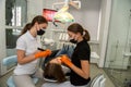 Dentist uses professional equipment to whiten the patient`s teeth in the clinic