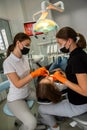 Dentist uses professional equipment to whiten the patient`s teeth in the clinic