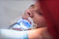 The dentist uses an ultraviolet lamp while fitting the girl with braces