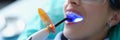 Dentist using dental ultraviolet curing light tool during procedure with patient in clinic