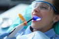 Dentist using dental ultraviolet curing light tool during procedure with patient in clinic