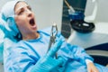 Dentist using surgical pliers to remove a decaying tooth.