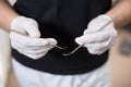 Dentist with white gloves holding dental equipment - mirror and sonde at the dental office