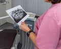 Dentist woman in pink uniform looking at roentgen of human jaw