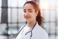 Dentist woman standing with crossed arms. Confident dentist standing in a hospital corridor in a white coat.