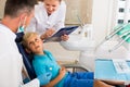 Dentist with woman assistant are diagnosticating to young patient which is sitting