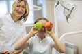 Dentist woman gives apple for smiling teenage girl in dental room