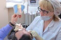 Dentist showing defects on patient teeth using blue gel and needle in dentistry.