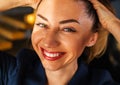 Partial portrait of a girl with strong white teeth looking at the camera and smiling, fingers near her face.