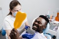 Dentistry. Dentist showing teeth color shades guide for tooth whitening for african patient in dental clinic. African is Royalty Free Stock Photo