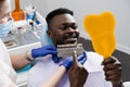 Dentistry. Dentist showing teeth color shades guide for tooth whitening for african patient in dental clinic. African is Royalty Free Stock Photo