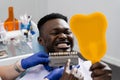 Dentistry. Dentist showing teeth color shades guide for tooth whitening for african patient in dental clinic. African is Royalty Free Stock Photo