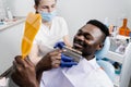 Dentistry. Doctor checking teeth color matching samples in dental clinic. Teeth whitening of african man. Dentist Royalty Free Stock Photo