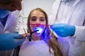 Dentists examining female patient with dental curing light