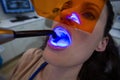 Dentists examining female patient with dental curing light