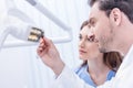 Dentists looking at xray picture of teeth in hand against dental lamp