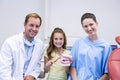 Dentists and young patient holding model teeth in dental clinic