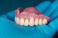 Denture. Full removable denture of the upper jaw of a man with white beautiful teeth in the hand of a dentist. Aesthetic Dentistry Royalty Free Stock Photo