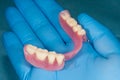 Denture. Partial removable denture of the lower jaw of a person with white beautiful teeth in the hand of a dentist. Aesthetic Royalty Free Stock Photo