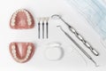 Dentures next to floss and metal pick and mirror