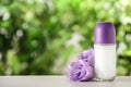 Deodorant container and Eustoma flowers on white wooden table against blurred background