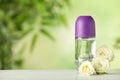 Deodorant container and roses on white wooden table against blurred background
