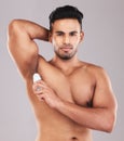 Deodorant, health and man cleaning armpit against a grey studio background. Wellness, care and portrait of a young model