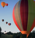 A departing hot air balloon in the foreground with others against the blue sky flying over the hills, in the foreground Royalty Free Stock Photo