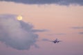 a departing plane at night, against backdrop of a full moon, sets off on its evening flight Royalty Free Stock Photo