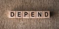 DEPEND word written on wooden blocks on a brown background