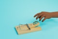 dependence on money. hand reaches for a mousetrap with a dollar on a blue background. 3D render