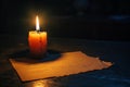 Depicting a  single candle burning in the darkness, casting its light on an empty paper letterhead. the simplicity of the scene i Royalty Free Stock Photo