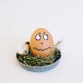 Depiction of an indignant face on an egg in a cute small plate on a white background